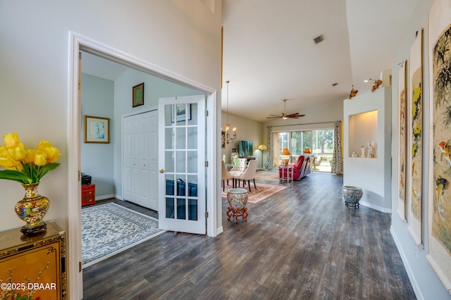 hall with dark hardwood / wood-style floors, a notable chandelier, and vaulted ceiling