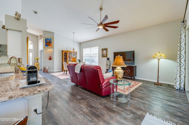 living room featuring ceiling fan with notable chandelier, sink, dark wood-type flooring, and vaulted ceiling