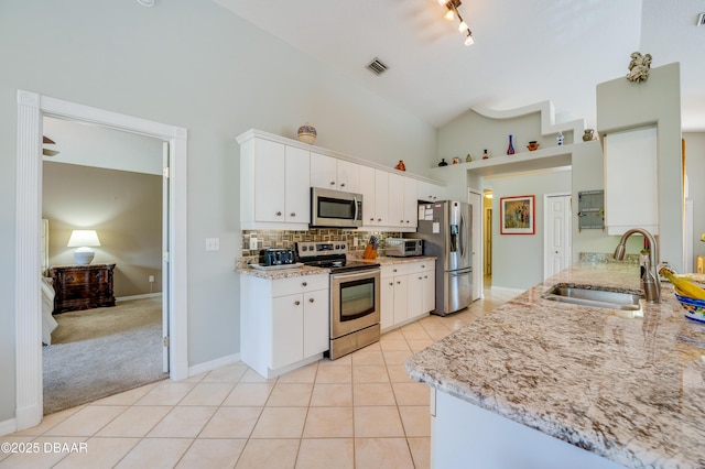 kitchen with white cabinetry, stainless steel appliances, high vaulted ceiling, light stone countertops, and sink