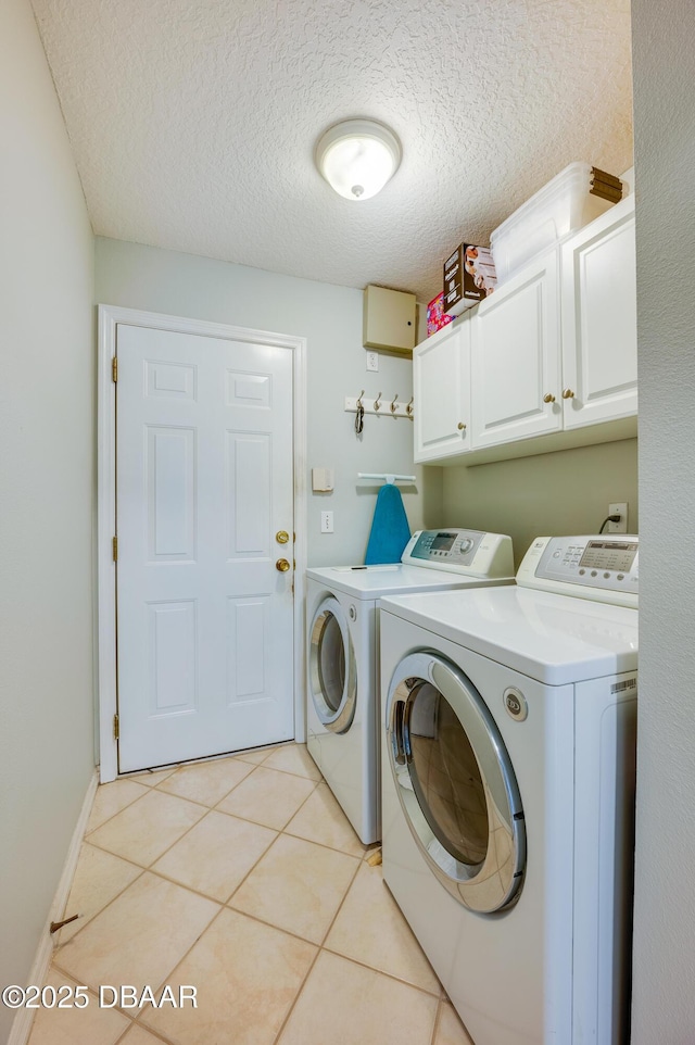 laundry room featuring cabinets, separate washer and dryer, light tile patterned floors, and a textured ceiling