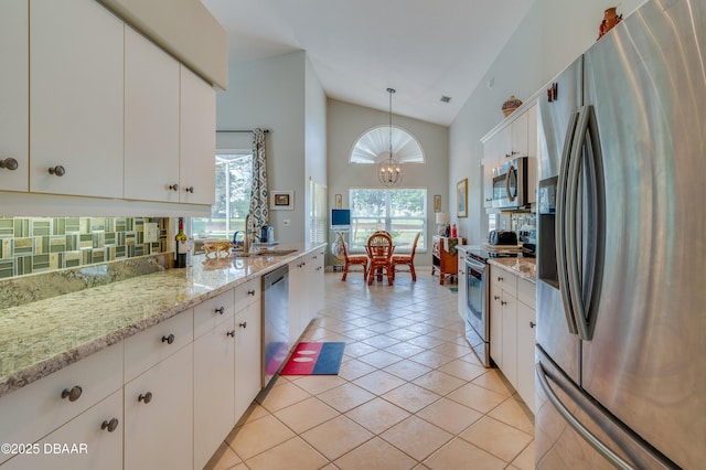 kitchen featuring white cabinetry, stainless steel appliances, tasteful backsplash, hanging light fixtures, and vaulted ceiling