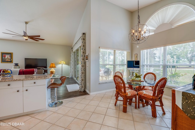 tiled dining area with ceiling fan with notable chandelier and high vaulted ceiling