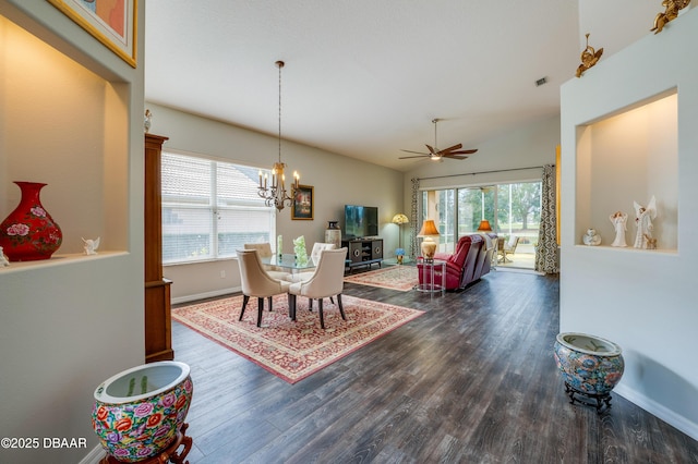 dining area with vaulted ceiling, dark wood-type flooring, ceiling fan with notable chandelier, and a wood stove