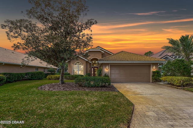 mediterranean / spanish home featuring a garage and a lawn