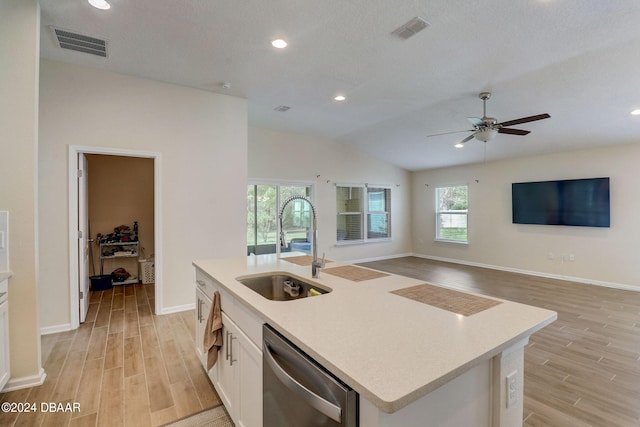 kitchen with lofted ceiling, white cabinets, sink, an island with sink, and stainless steel dishwasher