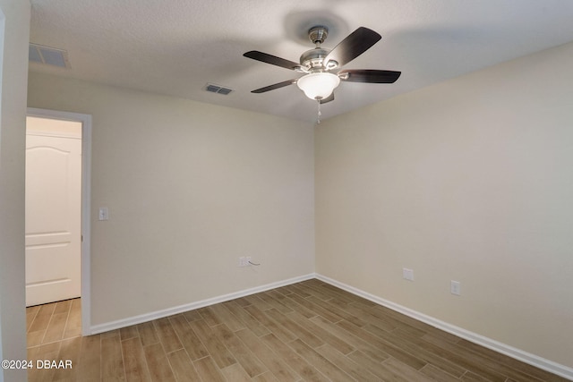 empty room with light hardwood / wood-style floors, ceiling fan, and a textured ceiling