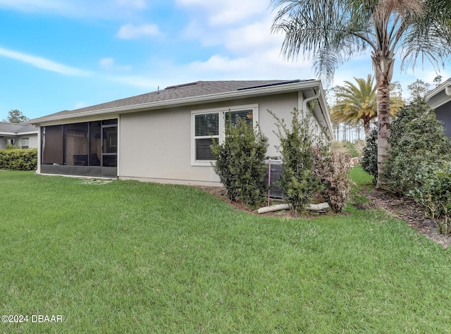 rear view of property featuring a sunroom and a lawn