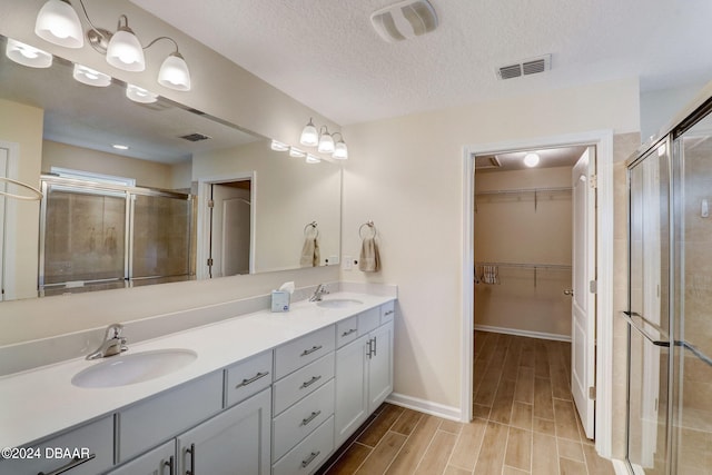 bathroom with walk in shower, vanity, and a textured ceiling