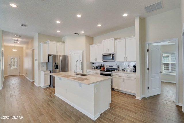 kitchen featuring stainless steel appliances, white cabinetry, sink, and a kitchen island with sink