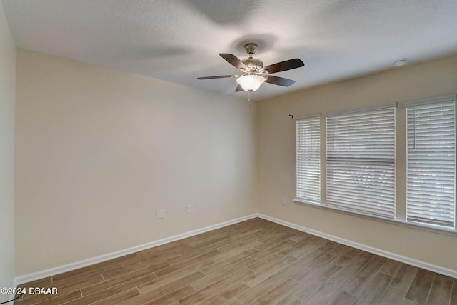 empty room with ceiling fan, a textured ceiling, and light hardwood / wood-style flooring