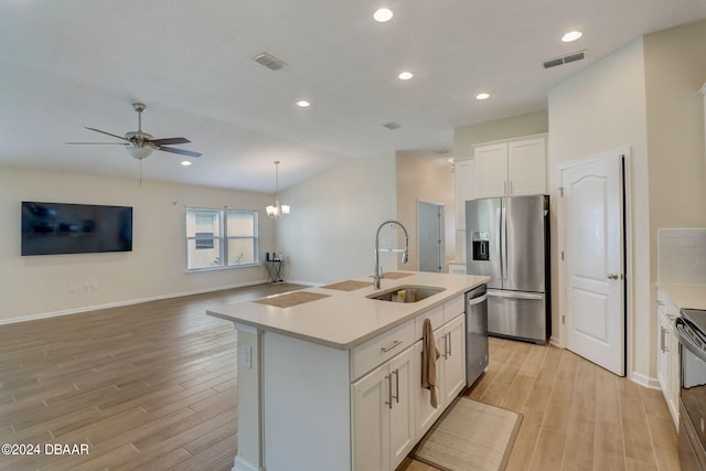 kitchen featuring stainless steel appliances, white cabinets, sink, an island with sink, and light wood-type flooring