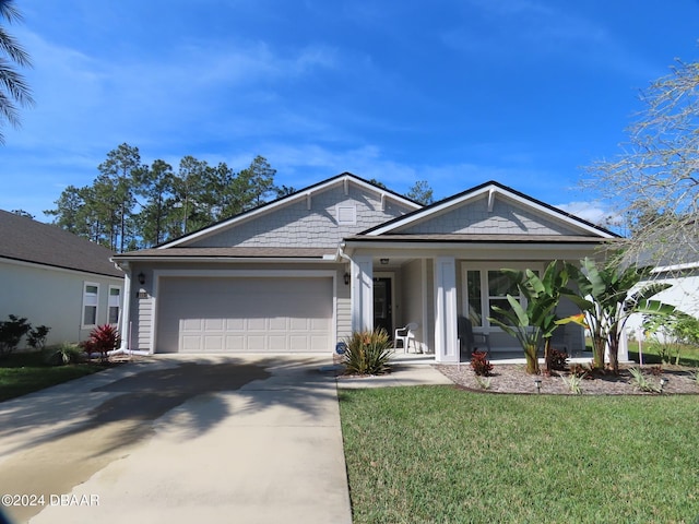 view of front of house featuring covered porch, a garage, and a front lawn