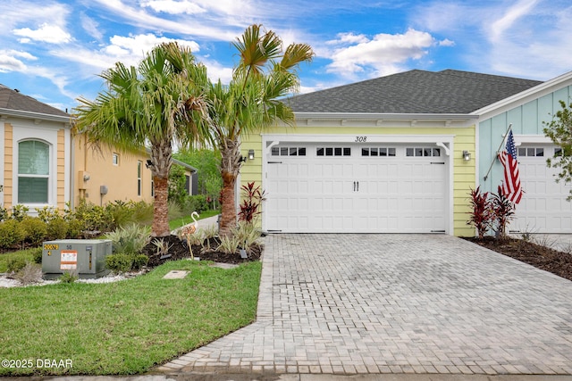 308 Low Tide Ln, Daytona Beach, FL 32124 - view of front of property with decorative driveway, a garage, board and batten siding, a front yard, and roof with shingles