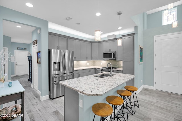 308 Low Tide Ln, Daytona Beach, FL 32124 - kitchen with appliances with stainless steel finishes, gray cabinets, light wood-type flooring, tasteful backsplash, and a breakfast bar area