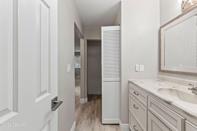 bathroom with hardwood / wood-style flooring, vanity, and a textured ceiling