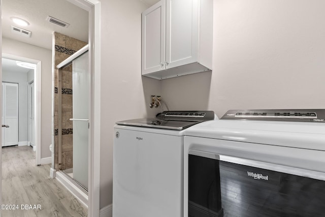 laundry room with cabinets, separate washer and dryer, and light hardwood / wood-style flooring