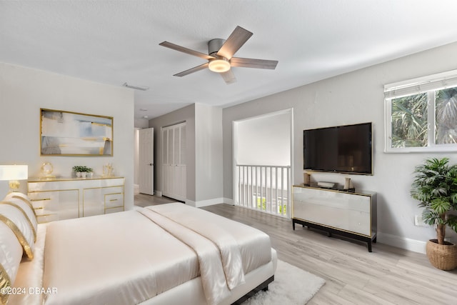 bedroom with light hardwood / wood-style flooring, ceiling fan, and a closet