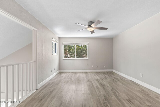 empty room with a textured ceiling, ceiling fan, and light hardwood / wood-style flooring