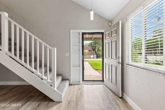 foyer featuring wood-type flooring, plenty of natural light, and lofted ceiling