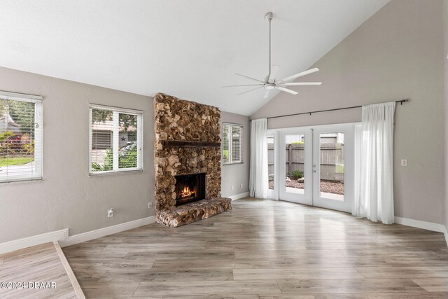 unfurnished living room with a wealth of natural light, lofted ceiling, ceiling fan, and light hardwood / wood-style flooring