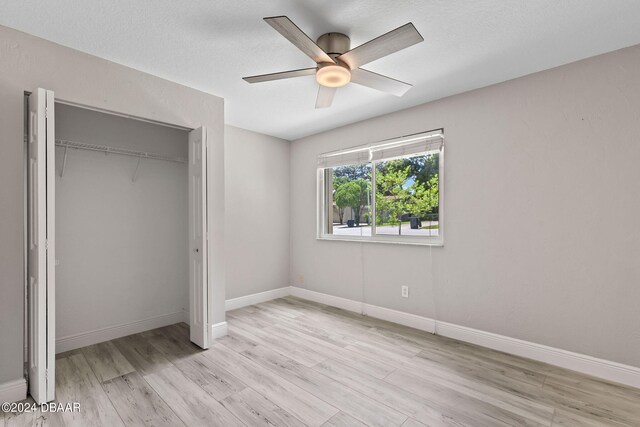 unfurnished bedroom with a closet, light wood-type flooring, and ceiling fan