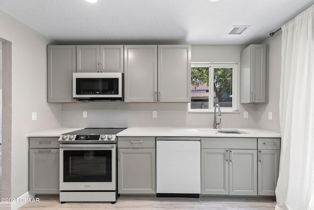 kitchen featuring gray cabinets, sink, light hardwood / wood-style floors, dishwasher, and stainless steel electric stove