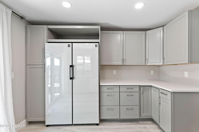 kitchen featuring refrigerator, gray cabinetry, a textured ceiling, and light hardwood / wood-style floors