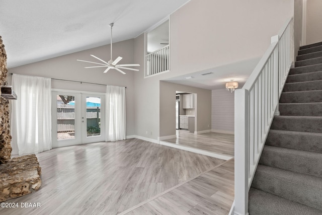 unfurnished living room with high vaulted ceiling, light wood-type flooring, french doors, and ceiling fan