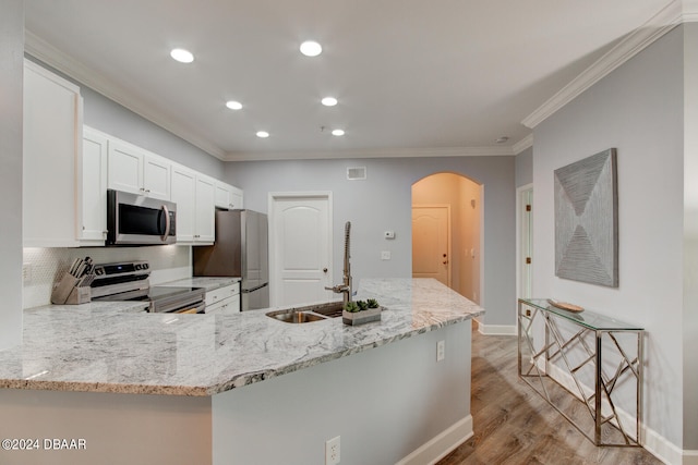 kitchen with white cabinetry, kitchen peninsula, stainless steel appliances, and light stone counters