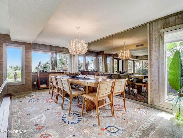 dining room featuring wooden walls, an inviting chandelier, and light hardwood / wood-style flooring