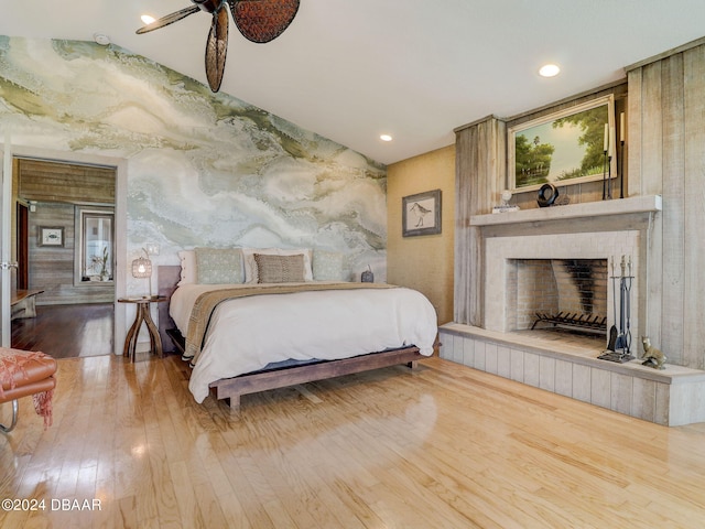 bedroom with hardwood / wood-style floors, a fireplace, and ceiling fan