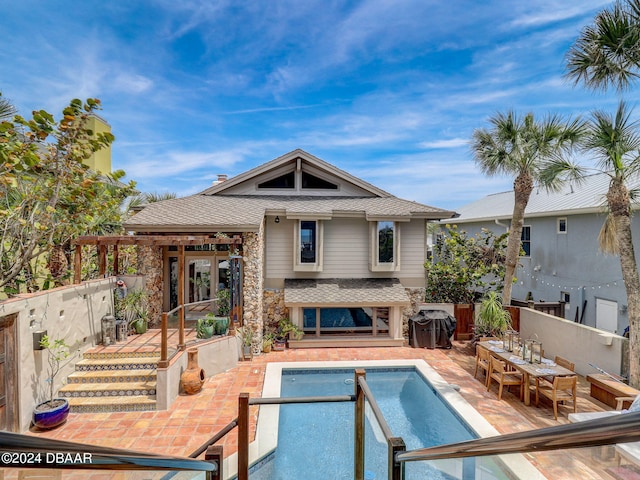 back of property with a fenced in pool and a patio