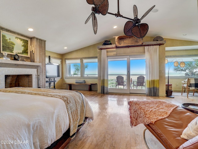 bedroom with access to outside, vaulted ceiling, a brick fireplace, and wood-type flooring