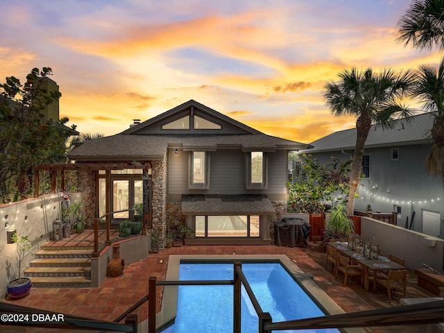 pool at dusk with a patio area