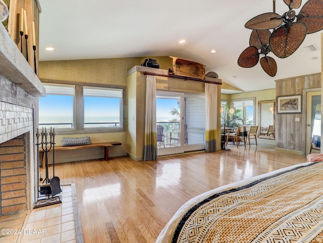 interior space featuring ceiling fan, vaulted ceiling, light hardwood / wood-style floors, and a brick fireplace