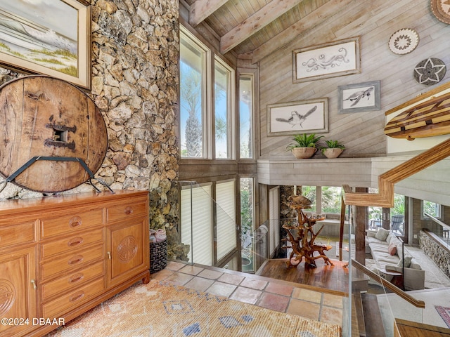 interior space featuring beam ceiling, high vaulted ceiling, wood walls, wood ceiling, and light hardwood / wood-style flooring