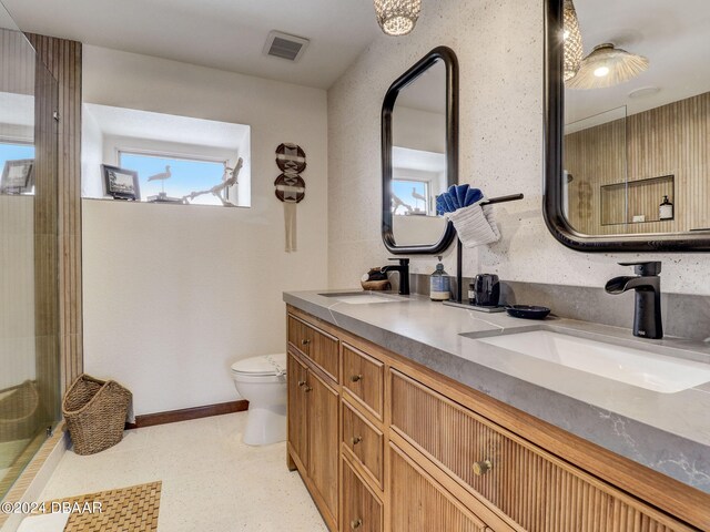 bathroom featuring toilet, vanity, walk in shower, and plenty of natural light