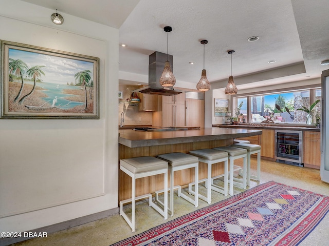 kitchen with wine cooler, a breakfast bar area, a textured ceiling, island exhaust hood, and pendant lighting