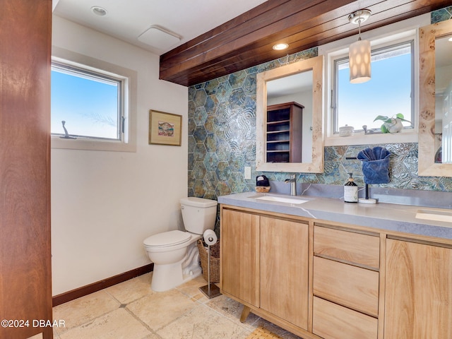 bathroom with toilet, vanity, a wealth of natural light, and decorative backsplash