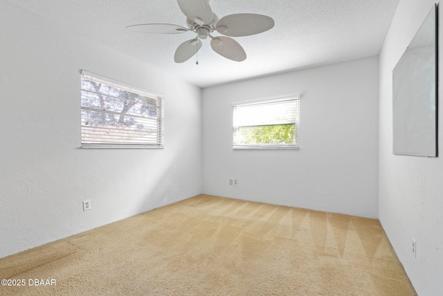 carpeted spare room featuring a textured ceiling and ceiling fan