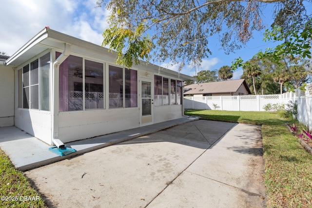 rear view of property with a patio, a lawn, and a sunroom