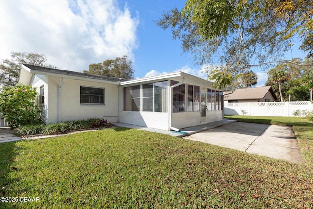 rear view of property with a sunroom, a patio area, and a yard