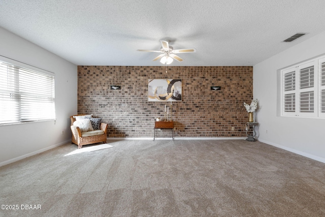 unfurnished room with carpet floors, a textured ceiling, and brick wall