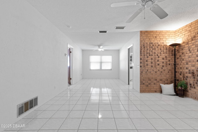 spare room with ceiling fan, brick wall, and a textured ceiling