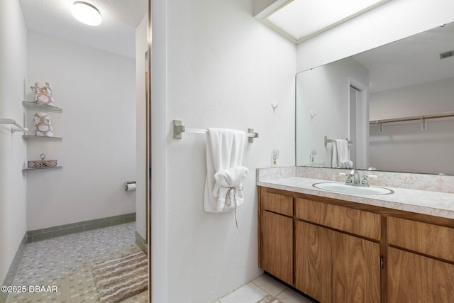 bathroom with tile patterned flooring, vanity, and a textured ceiling