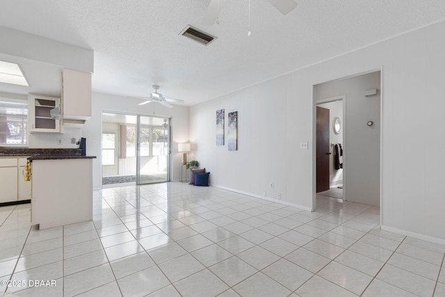 unfurnished living room with ceiling fan, light tile patterned flooring, and a textured ceiling