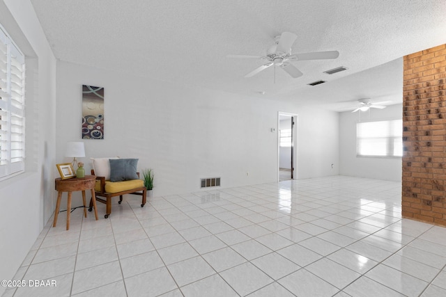 interior space featuring ceiling fan, light tile patterned floors, and a textured ceiling