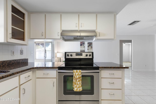 kitchen with kitchen peninsula, ventilation hood, light tile patterned floors, dark stone countertops, and stainless steel electric range