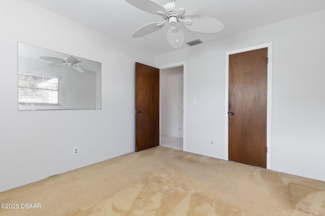 unfurnished bedroom featuring a textured ceiling, ceiling fan, light carpet, and a closet