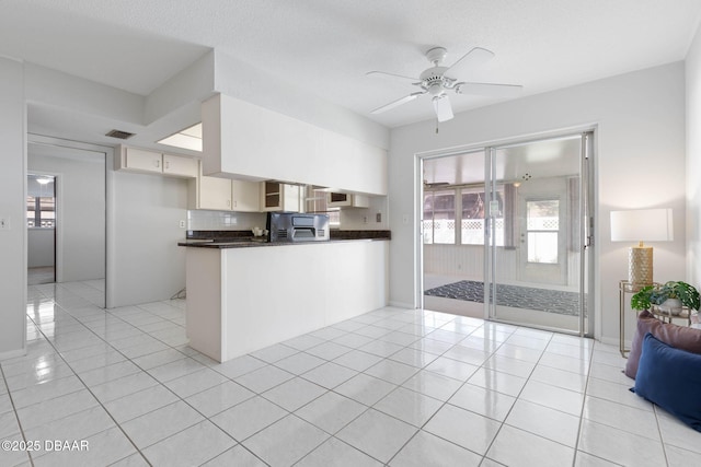 kitchen featuring kitchen peninsula, decorative backsplash, light tile patterned flooring, and ceiling fan